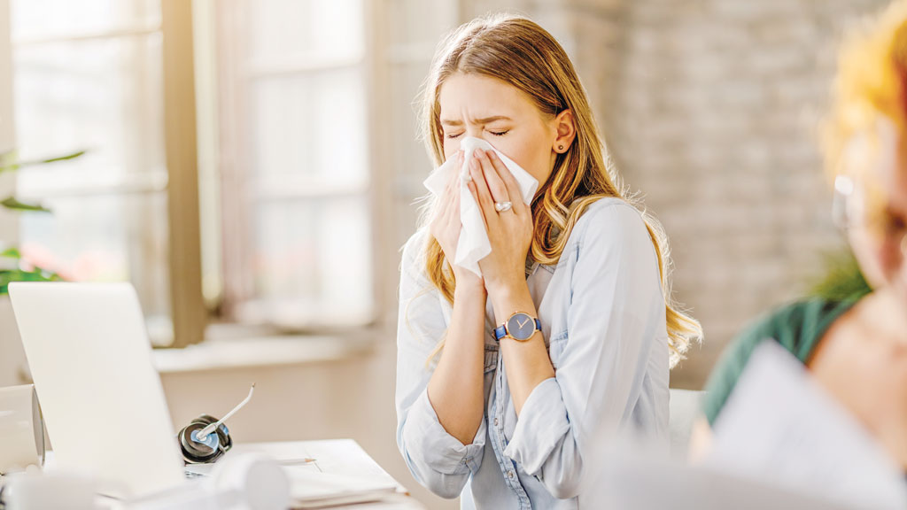 young-sick-businesswoman-sneezing-tissue-while-working-office